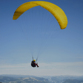 Someone flying over mountains using a yellow parachute